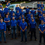 Hydro Savage Pressure Washing employees in company parking lot surrounded by service vehicles