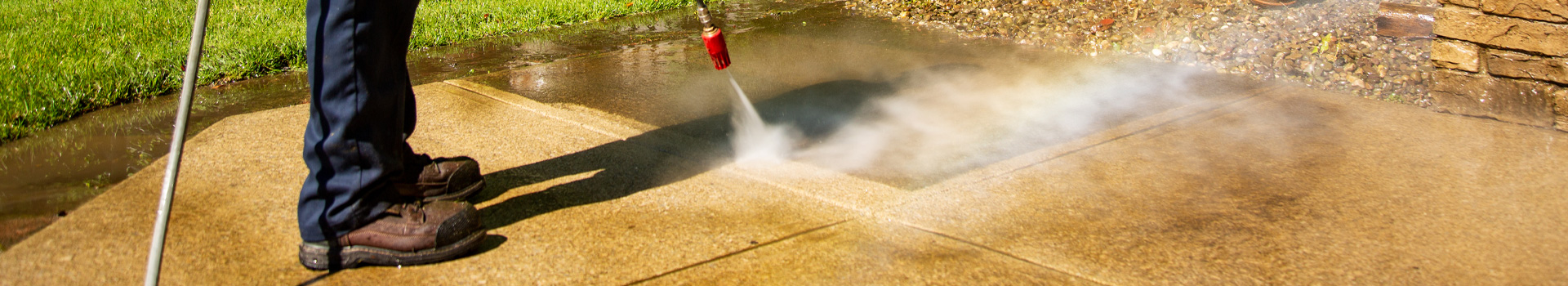 Power washing technician safely washing a concrete surface